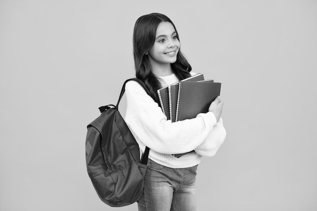 Scuola ragazza tenere quaderno e libro su sfondo giallo studio isolato Scuola e concetto di istruzione Ragazza adolescente in uniforme scolastica Faccia felice emozioni positive e sorridenti della ragazza adolescente