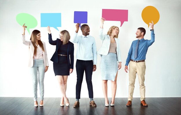 Scusa cosa hai detto Foto di un gruppo di colleghi di lavoro in piedi uno accanto all'altro mentre tengono i fumetti su uno sfondo bianco