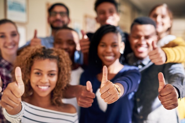 Se possiamo farlo, puoi anche tu Ritratto di un gruppo eterogeneo di studenti che mostrano i pollici in su al campus