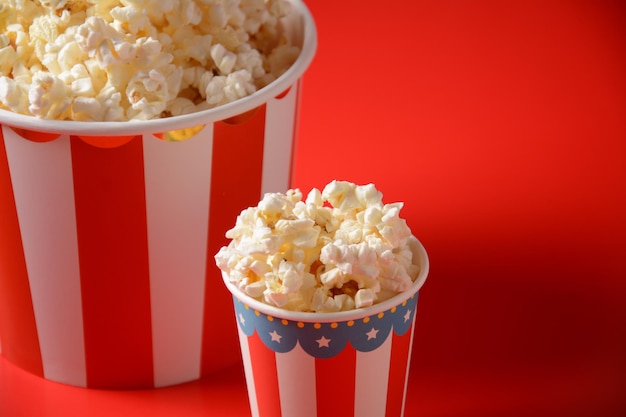Secchi con deliziosi popcorn su sfondo rosso. Popcorn rovesciati