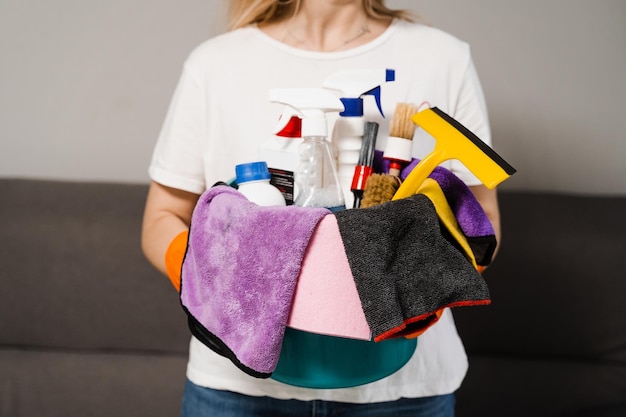 Secchio con panni detergenti e in microfibra per la pulizia della casa nelle mani del detergente Servizio professionale di pulizia domestica