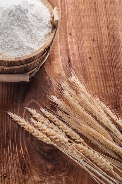 Secchio di legno con spighe di grano su tavola d'epoca