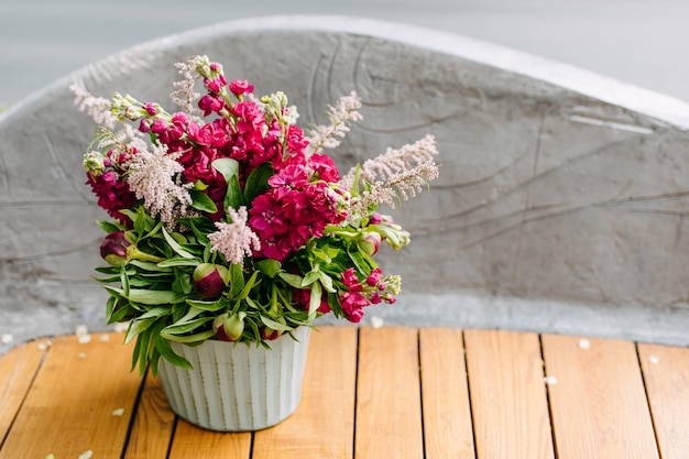 Secchio metallico con fiori rosa matthiola su una panca in legno