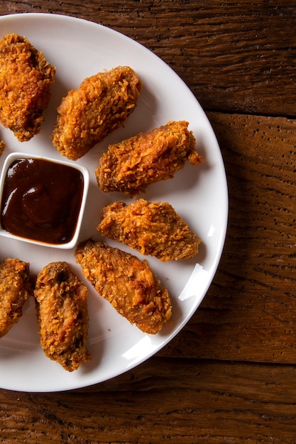 Secchio pieno di croccante pollo fritto kentucky con fumo e salsa barbecue su sfondo marrone. Messa a fuoco selettiva.