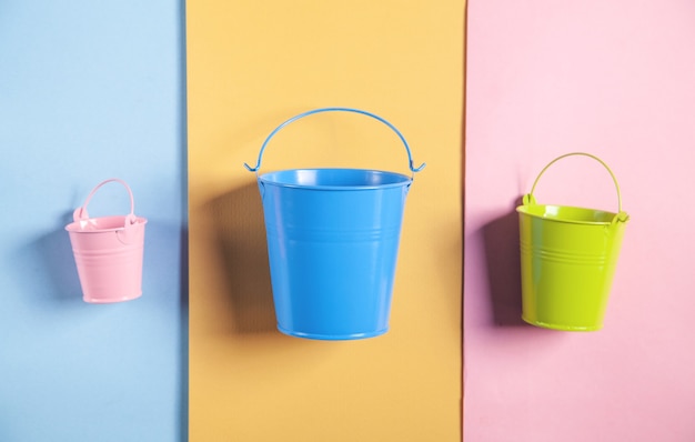 Secchio rosa, blu, verde sulla superficie della carta colorata.