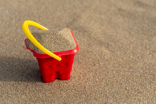 Secchio rosso del castello di sabbia sulla sabbia