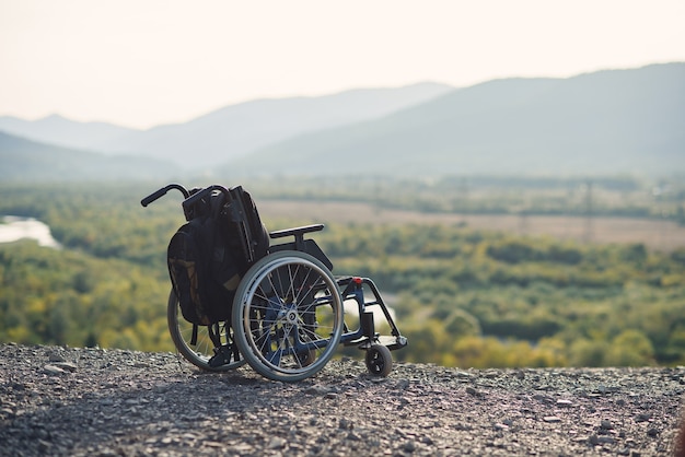 Sedia a rotelle vuota sulle montagne al tramonto. Concetto di viaggio di persone con disabilità.