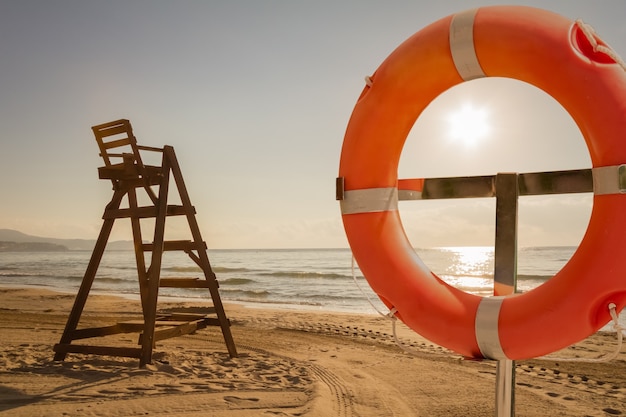 Sedia Baywatch e salvagente in una spiaggia al tramonto