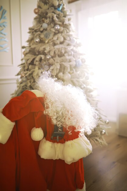 Sedia con vestiti di Babbo Natale. Costume da Babbo Natale appeso nella stanza bianca