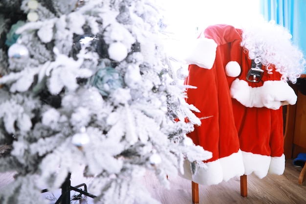 Sedia con vestiti di Babbo Natale. Costume da Babbo Natale appeso nella stanza bianca