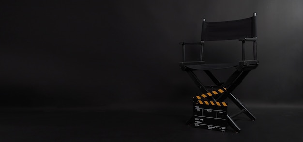 Sedia da regista e batacchio o lavagna per film utilizzati nella produzione video o nell'industria cinematografica e cinematografica. È messo su sfondo nero.