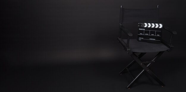 Sedia da regista nera e ciak o ardesia cinematografica. Uso IT nella produzione video o nell'industria cinematografica e cinematografica. È di colore nero.
