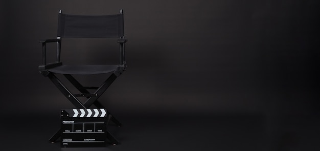 Sedia da regista nera e ciak o ardesia cinematografica. Uso IT nella produzione video o nell'industria cinematografica e cinematografica. È di colore nero.