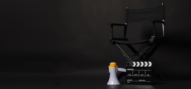 Sedia da regista nera e Clapper board o film Clapperboard con megafono su sfondo nero da utilizzare nella produzione video o nell'industria cinematografica