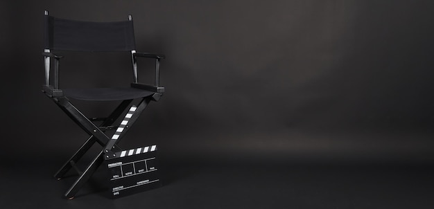 Sedia di regista nera e tavolo di clapper nero o ardesia cinematografica su terreno nero nero
