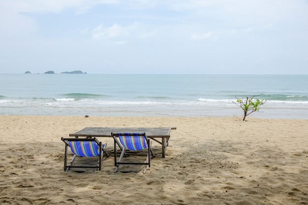 Sedia di spiaggia sulla sabbia bianca con l'onda del mare e soleggiato.