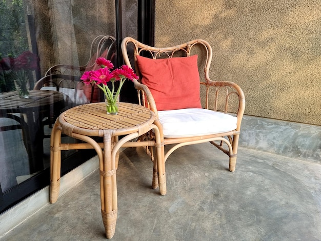 Sedia e tavolo in rattan con fiore gerbera magenta per angolo relax