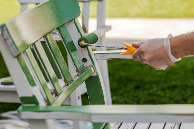 Sedia in legno dipinto. Ristrutturazione o rinnovamento di mobili da giardino in legno con rullo di vernice in verde