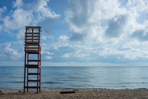 Sedia in legno Lifeguard sulla spiaggia con sabbia marrone mare.