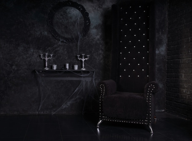Sedia nera con schienale alto e candelabri ricoperti di ragnatele nell'ambientazione inquietante di una casa stregata di Halloween