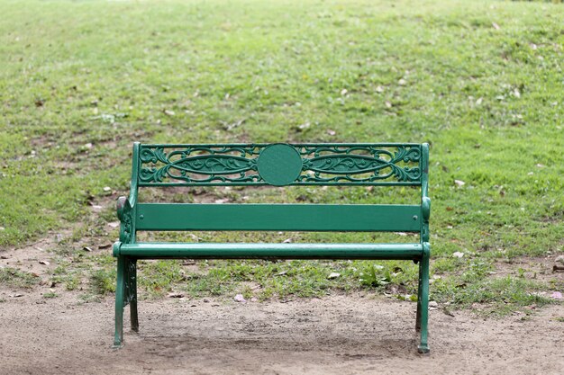 Sedia o banco verde su terra in parco pubblico e nessuno.