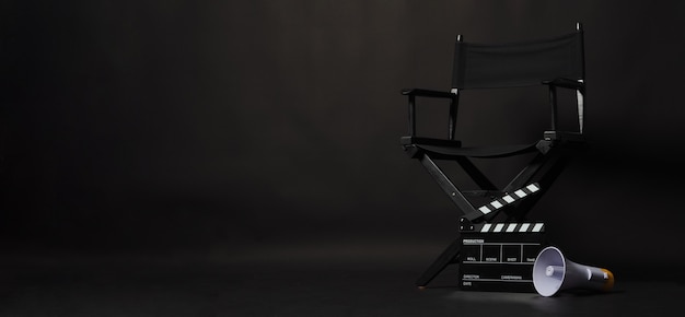 Sedia regista nera e ciak o ciak film con megafono su sfondo nero. utilizzare nella produzione video o nell'industria cinematografica