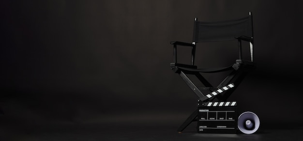Sedia regista nera e ciak o ciak film con megafono su sfondo nero. utilizzare nella produzione video o nell'industria cinematografica
