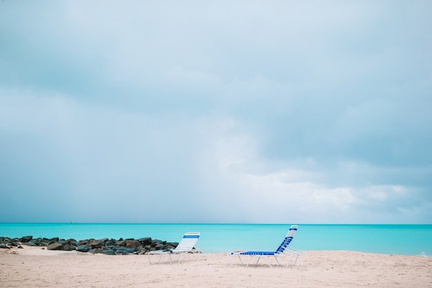 Sedie a sdraio bianche su una bellissima spiaggia tropicale alle Maldive