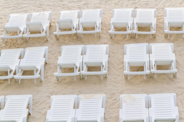 Sedie a sdraio bianche sulla spiaggia.