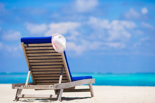 Sedie a sdraio con cappello sulla spiaggia bianca tropicale