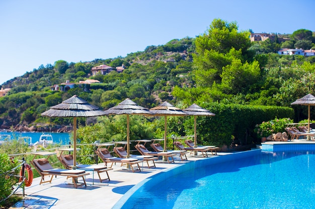 Sedie a sdraio e ombrelloni in legno vicino alla piscina a sfioro in resort di lusso