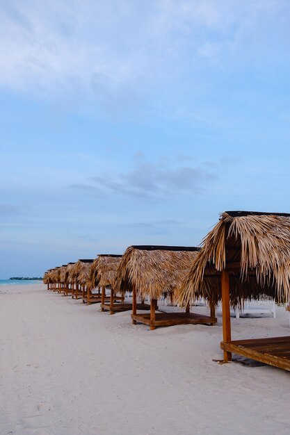 Sedie a sdraio e ombrelloni prima del tramonto su una spiaggia deserta.