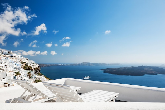 Sedie a sdraio in terrazza con vista mare. Architettura bianca sull'isola di Santorini, Grecia.