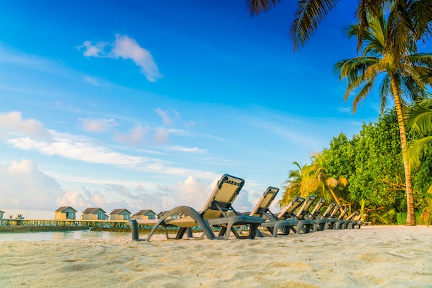 Sedie a sdraio nell&#39;isola delle Maldive con ville sull&#39;acqua al tempo dell&#39;alba.