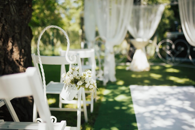 Sedie bianche decorate da un mazzo di fiori bianchi si preparano al matrimonio