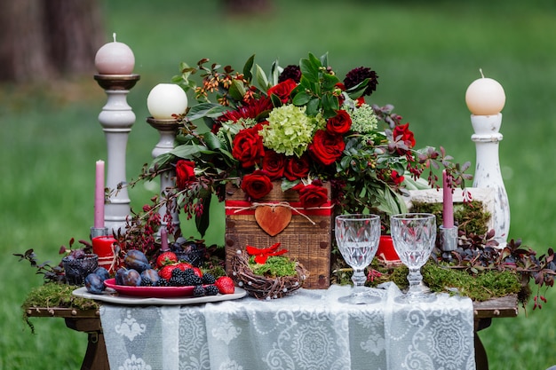 Sedie e candele, fiori, piatti in ceramica con frutta, in piedi sulla tovaglia di pizzo e muschio