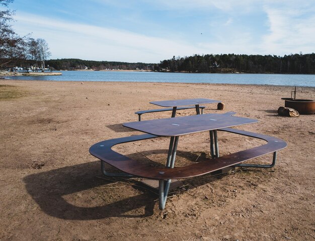 Sedie e tavoli vuoti sulla spiaggia accanto al lago contro il cielo