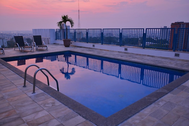 Sedie e tavolo vicino alla piscina contro il cielo durante il tramonto