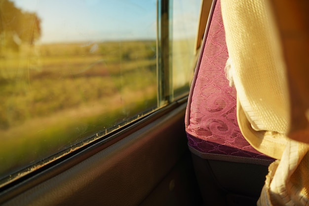 Sedile in minibus vicino al finestrino, illuminato dal sole, dettaglio in primo piano da dietro - concetto di viaggio