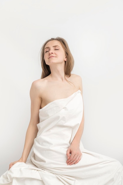 Seducente giovane donna vestita di foglio su sfondo bianco Ritratto di ragazza caucasica nuda ricoperta di foglio