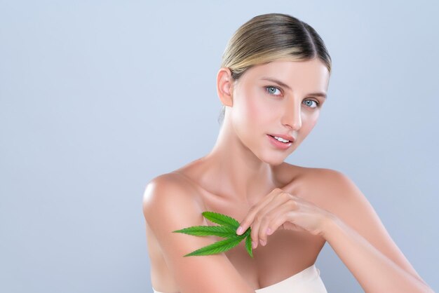 Seducente ritratto di bella donna tenere foglia verde come concetto di cura della pelle di cannabis