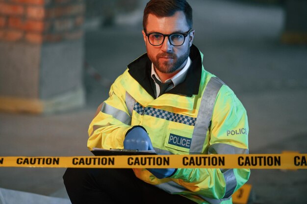 Seduto a pensare, un detective sta raccogliendo prove in una scena del crimine sul cantiere.