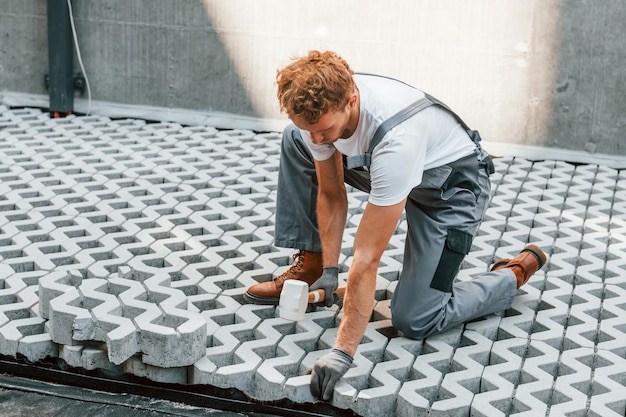 Seduto all'aperto Giovane che lavora in uniforme alla costruzione durante il giorno