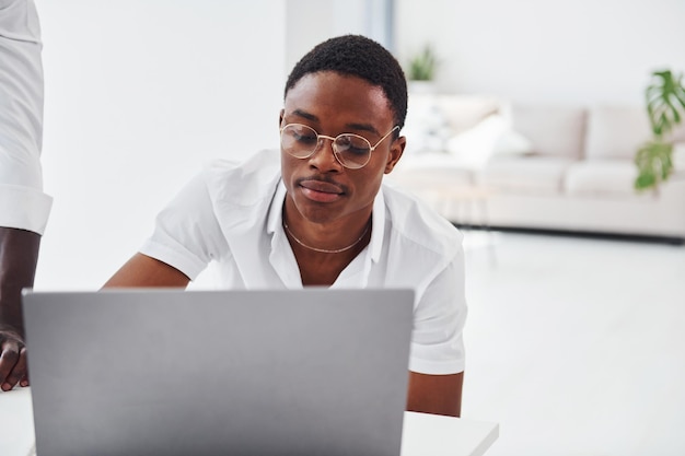Seduto con il computer portatile Gruppo di uomini d'affari afroamericani che lavorano insieme in ufficio