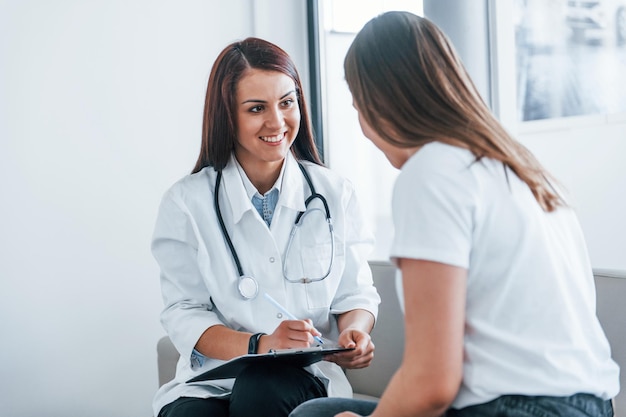 Seduto e parlando La giovane donna ha una visita con la dottoressa nella clinica moderna