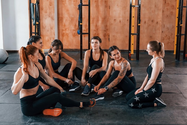 Seduto sul pavimento Un gruppo di giovani sportivi ha una giornata di crossfit al chiuso in palestra