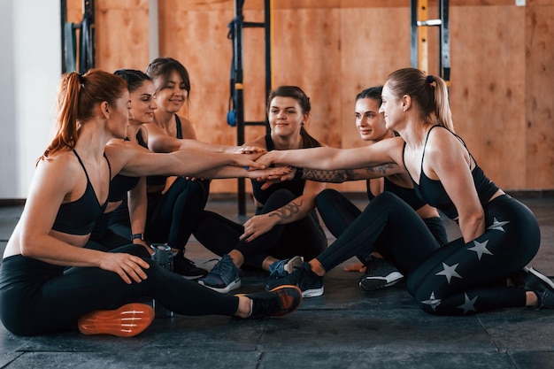 Seduto sul pavimento Un gruppo di giovani sportivi ha una giornata di crossfit al chiuso in palestra