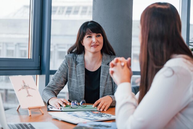 Seduto vicino al tavolo Due donne in abiti formali sono al chiuso nell'ufficio moderno lavora insieme