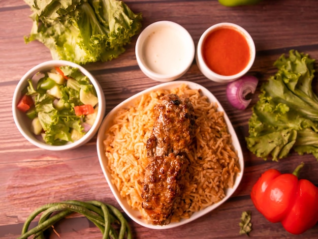 Seekh kabab biryani con insalata di salsa raita e bevanda isolata su sfondo di legno vista dall'alto del cibo indiano e pakistano