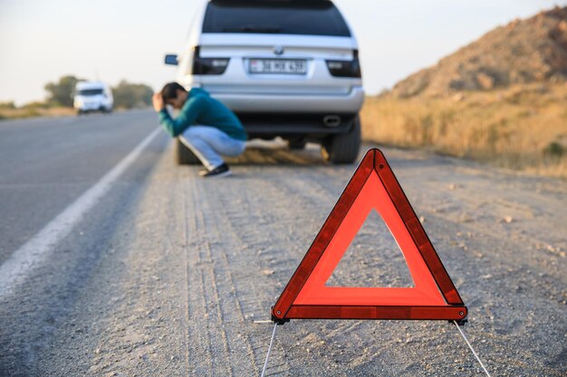 Segnale di arresto di emergenza rosso e automobile d'argento rotta